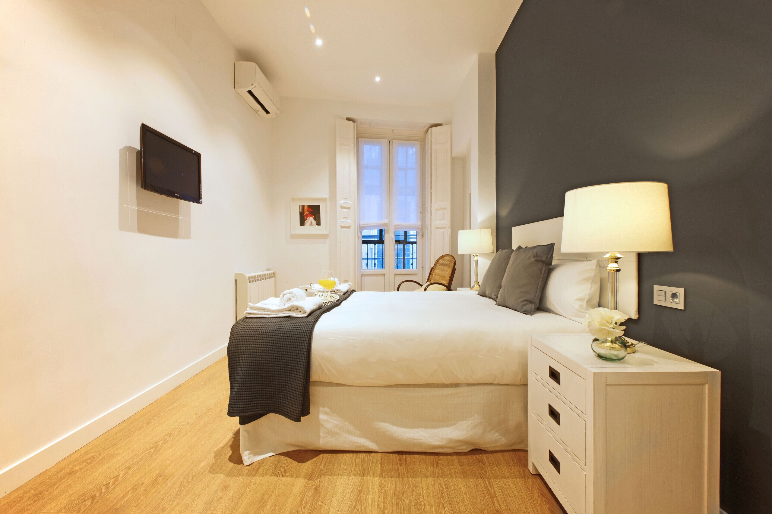 Une chambre d’hôtel moderne dotée d’un grand lit, de tables de chevet, d’un téléviseur à écran plat et d’une fenêtre offrant une vue agréable.