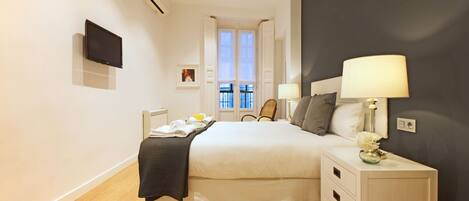 Une chambre d’hôtel moderne dotée d’un grand lit, de tables de chevet, d’un téléviseur à écran plat et d’une fenêtre offrant une vue agréable.