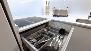 Una cocina con estufa integrada, tostadora y organizador de cajones con utensilios.