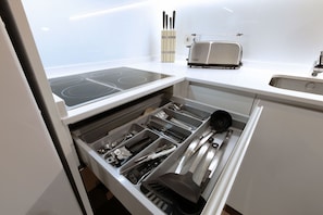 Una cocina con estufa integrada, tostadora y organizador de cajones con utensilios.
