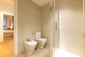 Ein modernes Badezimmer mit Toilette, Bidet und einer Duschkabine aus Glas.
