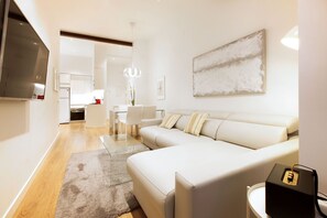 Ein modernes Wohnzimmer mit einem großen weißen Sofa, einem Flachbildfernseher und einer minimalistischen Einrichtung.