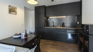 A modern kitchen with dark cabinetry, a wooden countertop, a built-in oven, and a dining area with a table and chairs. - Amazing Downtown Apt with balcony and fantastic view (Lisboa)