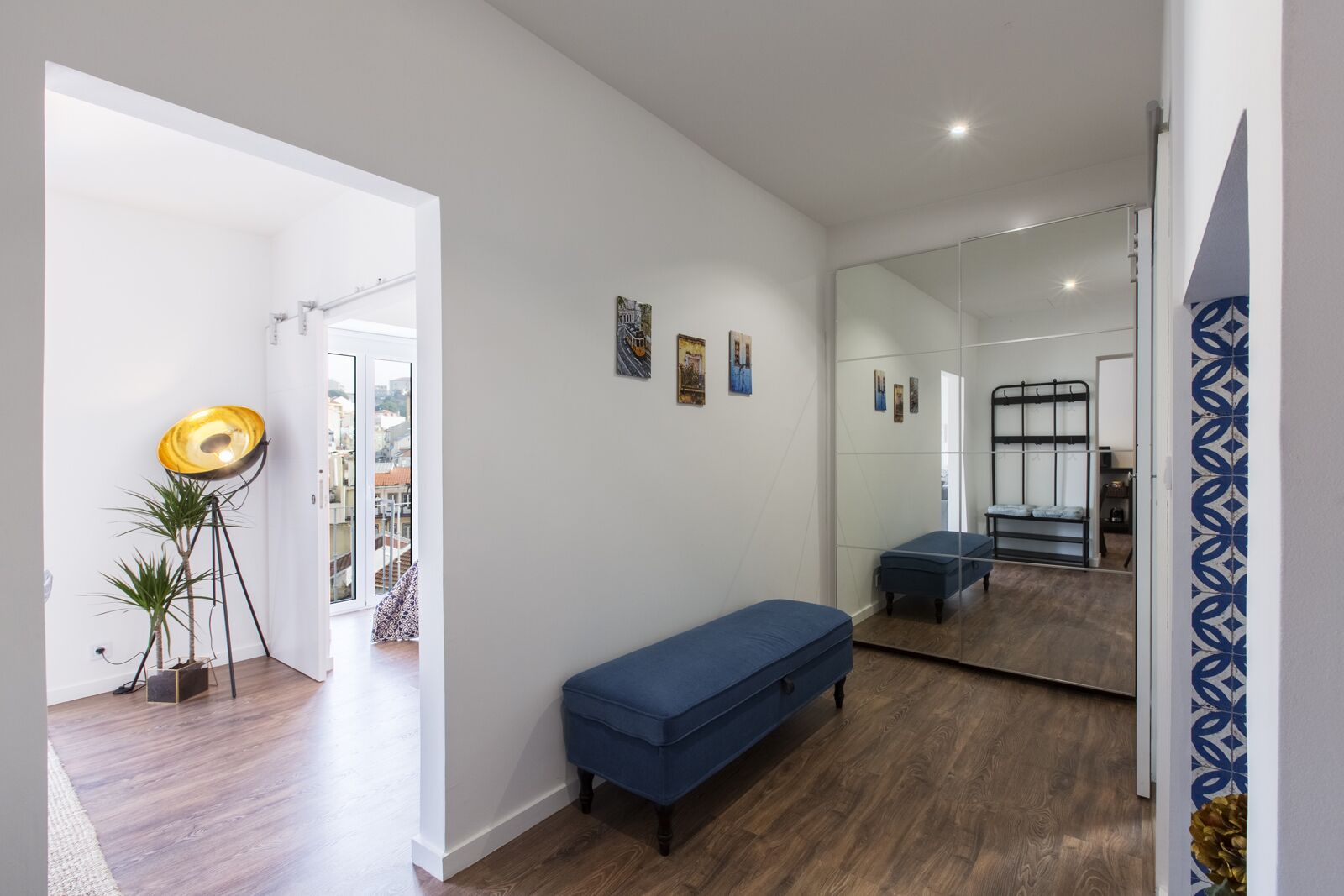 Ein modernes Interieur mit einer Bank, einer Stehlampe und einem Spiegel, der ein Etagenbett reflektiert.