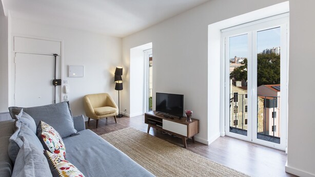 A modern living room with a sofa, a chair, a TV, and a floor lamp. - Amazing Downtown Apt with balcony and fantastic view (Lisboa)