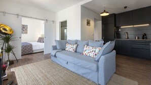 A modern apartment with a grey sofa, a small kitchen, and a separate bedroom. - Amazing Downtown Apt with balcony and fantastic view (Lisboa)