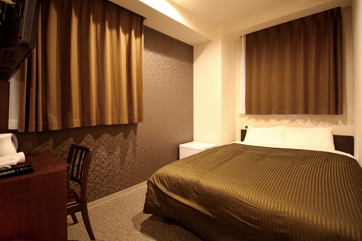 Ein Hotelzimmer mit Bett, Schreibtisch, Stuhl und Fernseher.