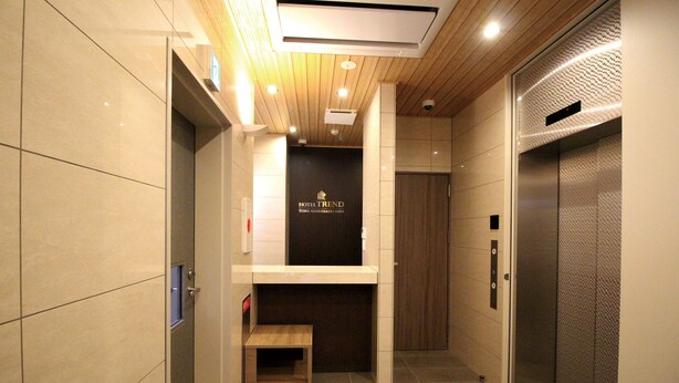 A modern elevator interior with a wooden panel ceiling, a small wooden bench, and a sign reading "HOTEL TREND". - Hotel Trend Tobu Asakusa-Eki Kita (Tokyo)