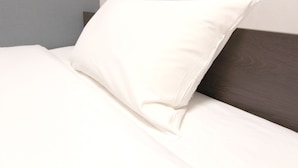A neatly made bed with a white pillow and a dark wooden headboard. - Hotel Trend Tobu Asakusa-Eki Kita (Tokyo)