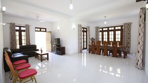 Un salón amplio con sofá, sillones, televisor y zona de comedor con mesa y sillas.