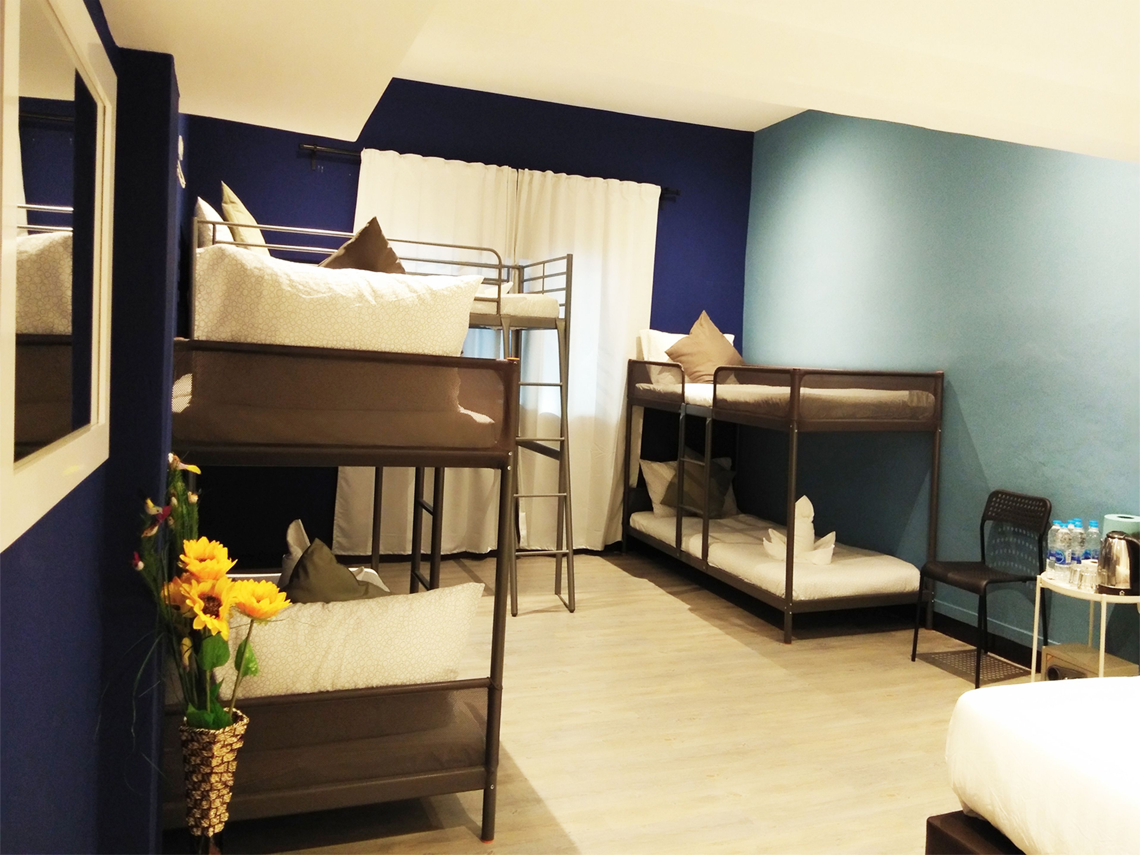 A room with bunk beds, a small table with bottles, and a chair.