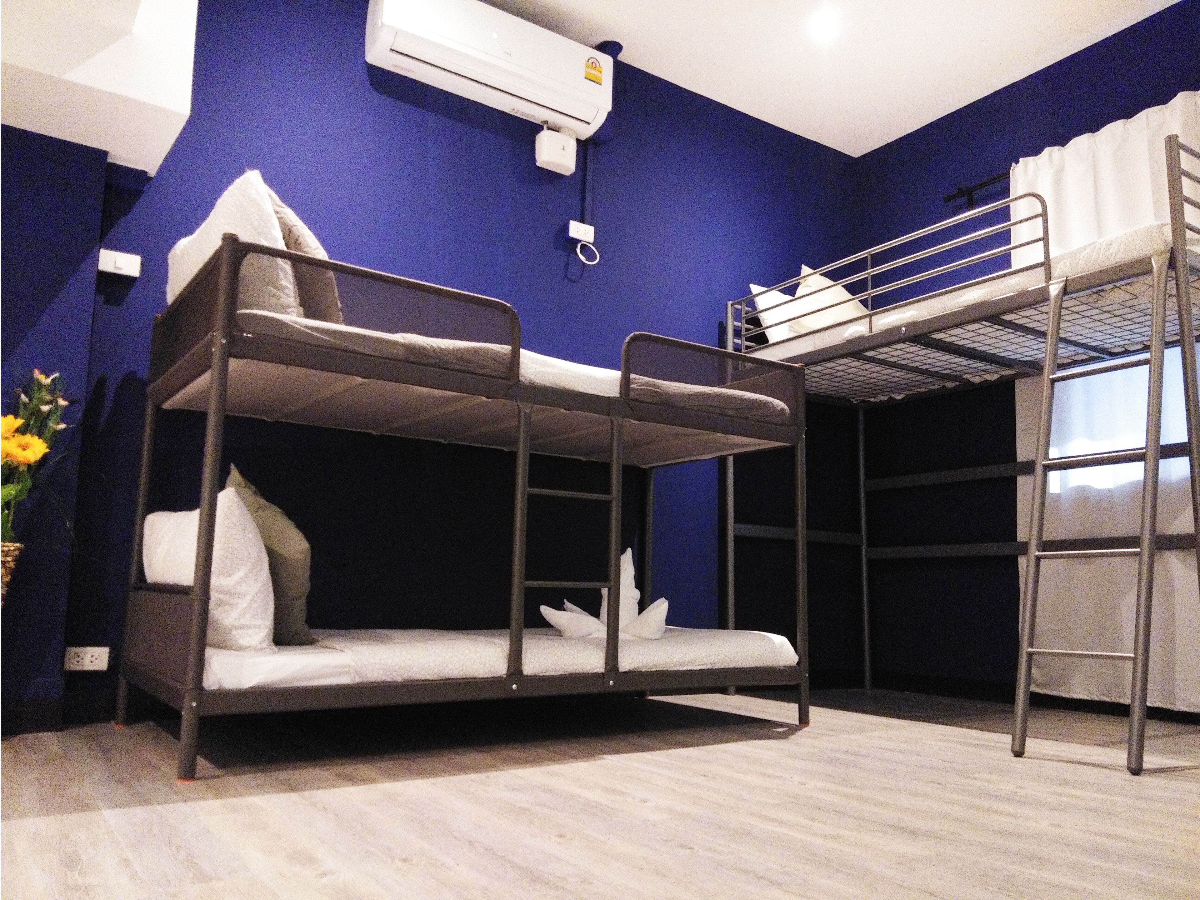 Habitación con literas, pared azul, ventana y unidad de aire acondicionado blanca.