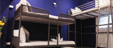 A bunk bed room with a blue wall, a window, and a white air conditioning unit.