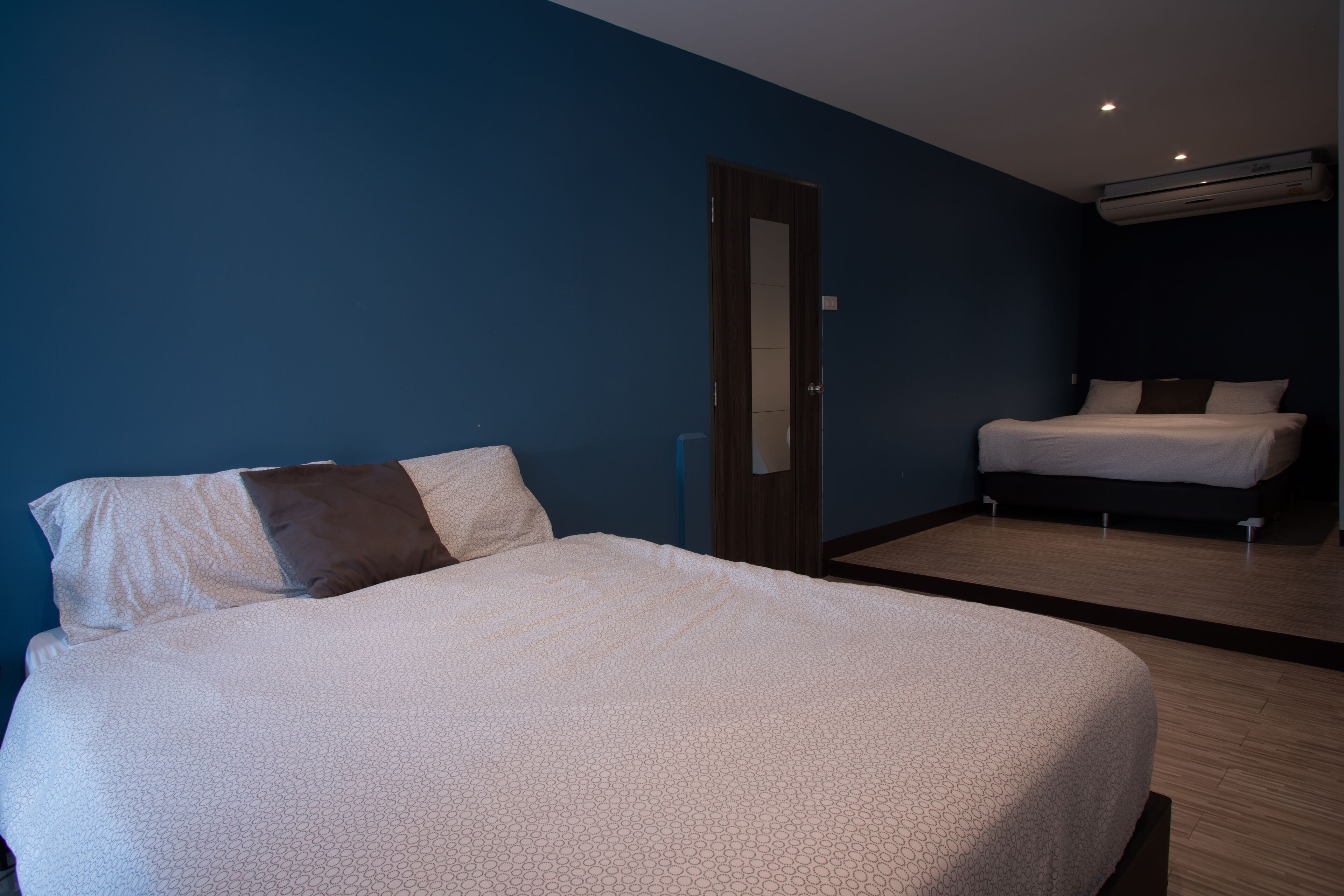 A hotel room with a large bed, a smaller bed, and a mirror on the wall.