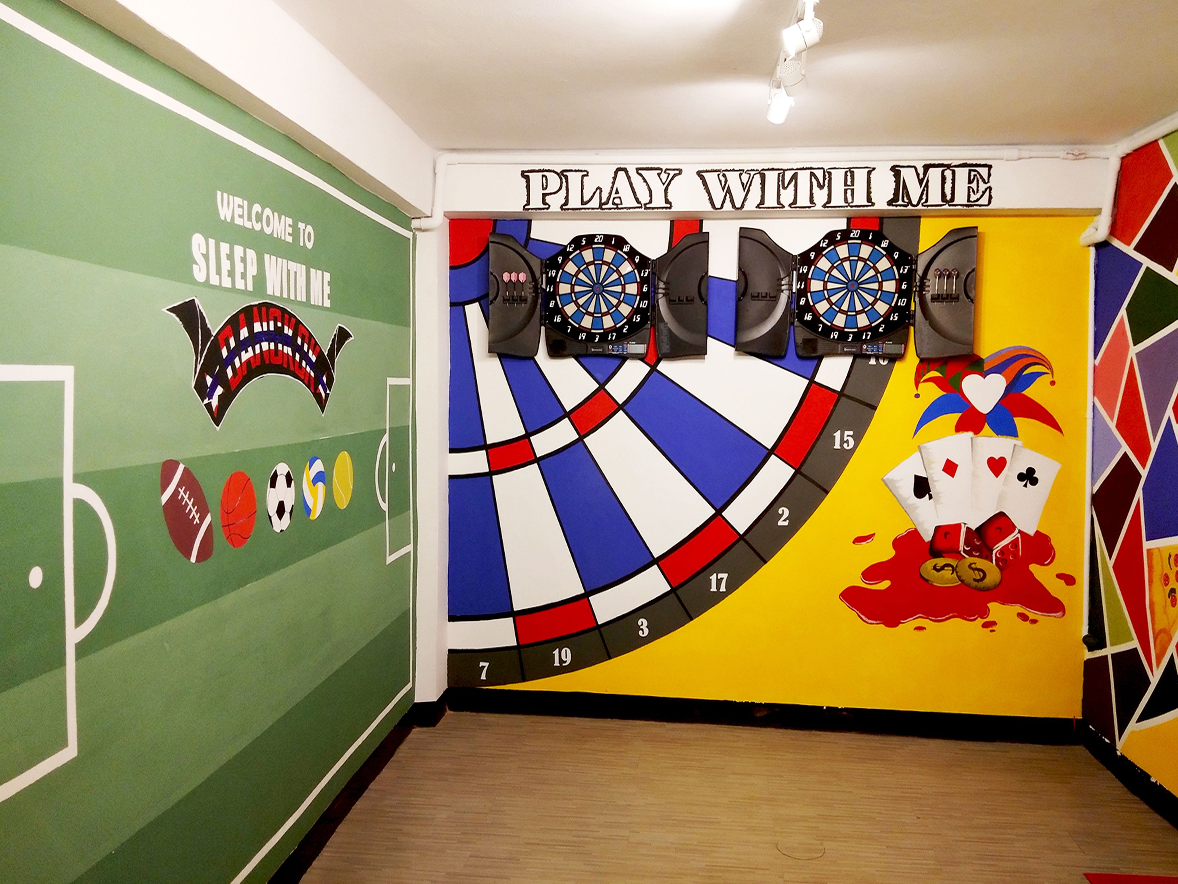 A room with a dartboard, a welcome sign, and sports-themed decorations.
