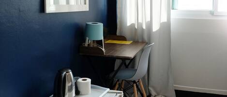 A compact room with a kitchenette, a table with chairs, a window with curtains, and an air conditioning unit.