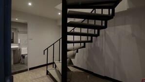 A modern interior with a staircase, a bathroom with a sink and toilet, and a shower area. - Sleep With Me Bangkok - BTS Phra Khanong (Bangkok)