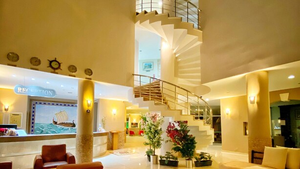 Un vestíbulo espacioso con una escalera central, zonas de estar y un mostrador de recepción.