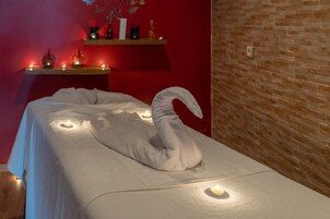 Una mesa de masaje con una toalla en forma de cisne y velas.
