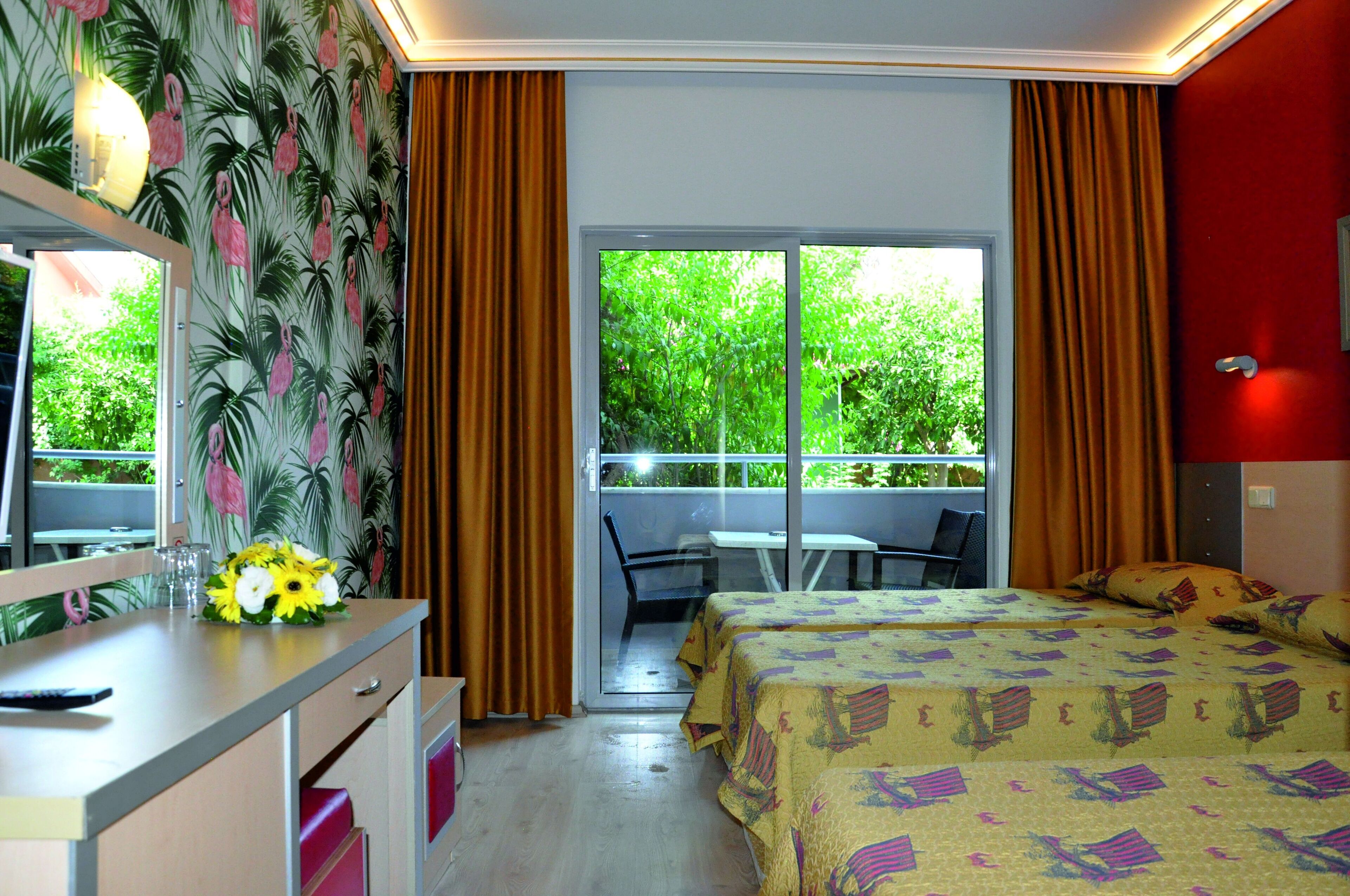 Habitación de hotel con cama, escritorio con un florero, una silla y balcón con mesa y sillas.