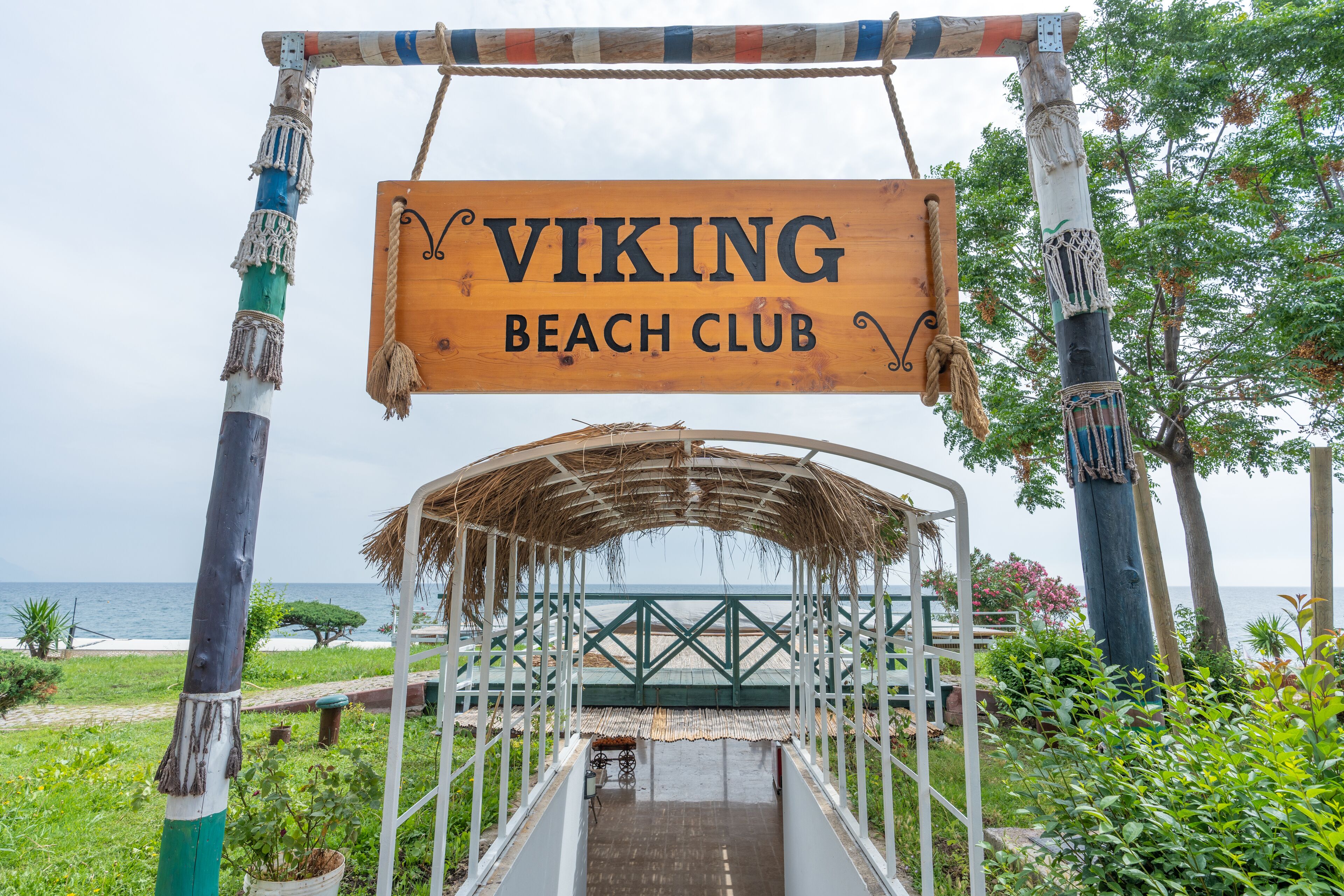 A wooden sign reading "VIKING BEACH CLUB" with a thatched roof structure in the foreground.