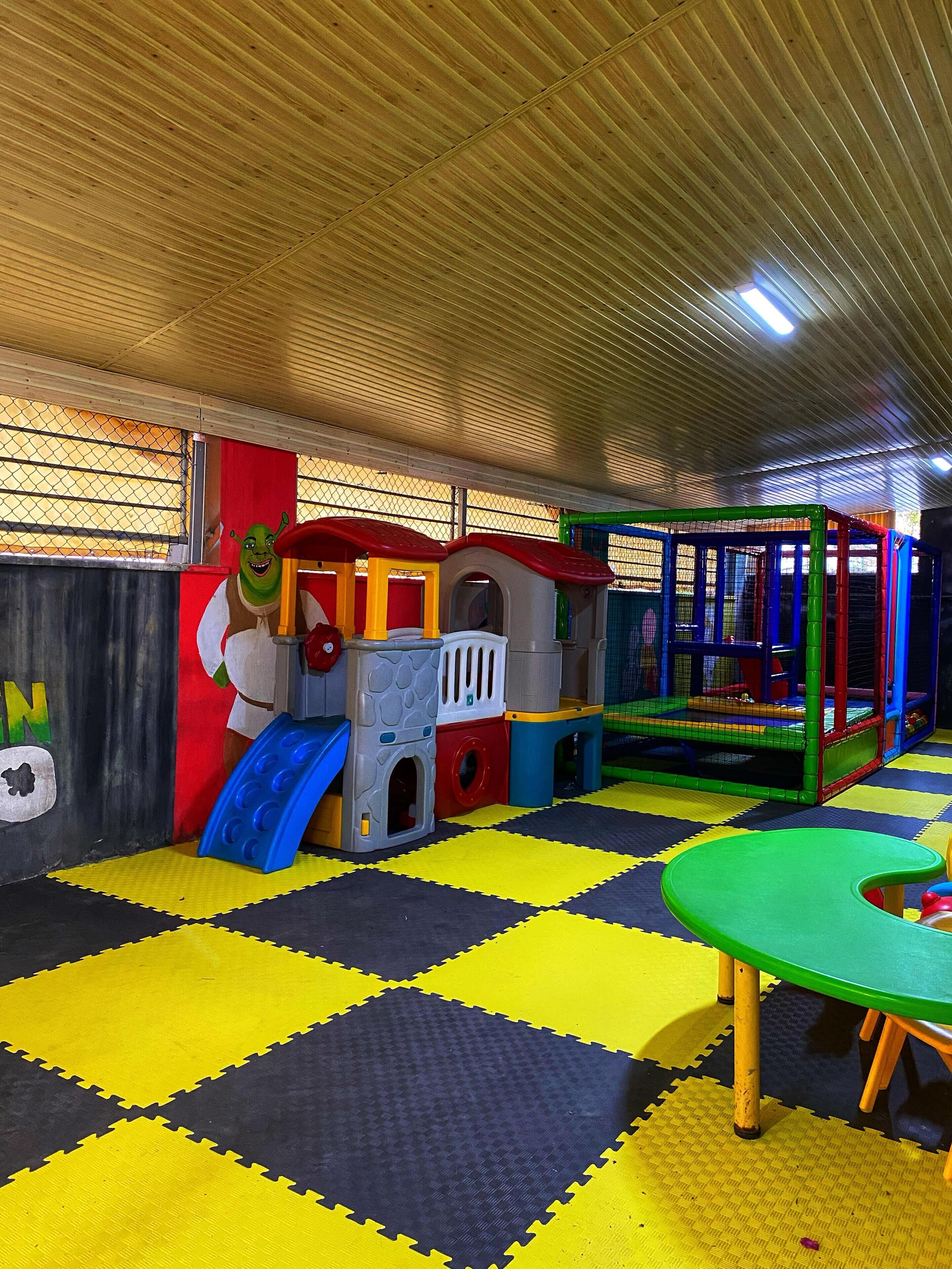 Un espace de jeux équipé d’un toboggan, de structures d’escalade et d’un parc à jeux avec des filets de protection.