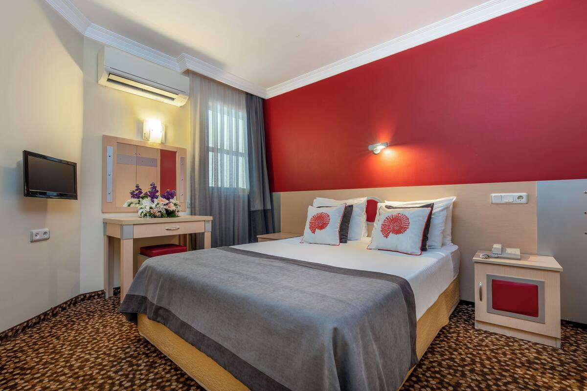 A hotel room with a bed, a desk, a TV, and a nightstand.