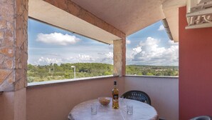 Ein Balkon mit Tisch, Stühlen, einer Flasche und einer Schüssel.
