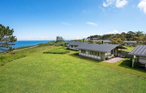 A coastal property with multiple cabins, a grassy lawn, and a view of the sea.