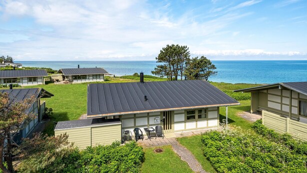 A coastal property with multiple cabins, each featuring a flat roof and a view of the sea.