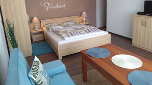 A bedroom with a bed, bedside tables, a wardrobe, a TV, and a desk with a chair.