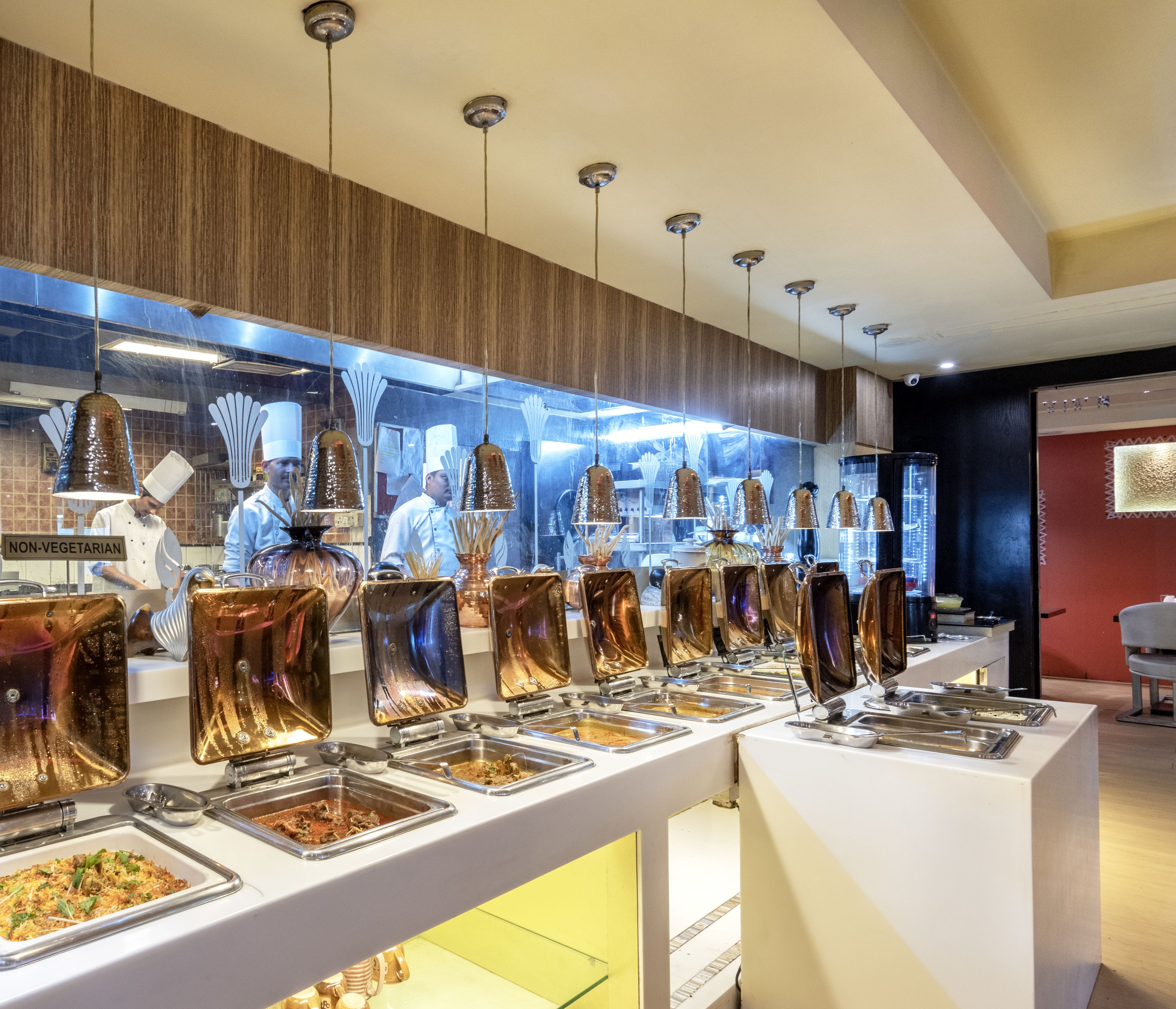 A buffet area with multiple food stations and a chef preparing food.