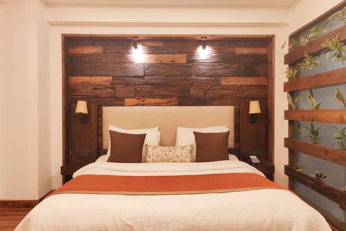A bed with a wooden headboard, two wall-mounted lamps, and a plant shelf.