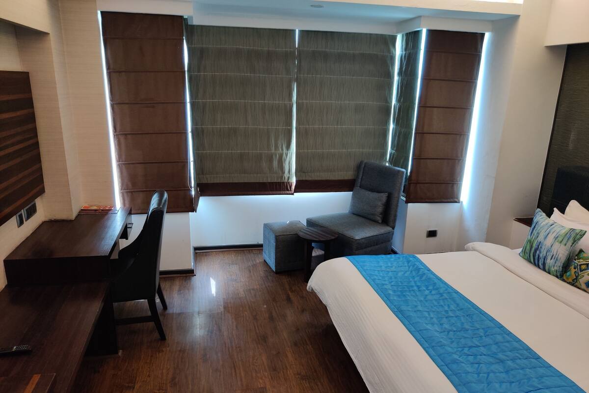 A hotel room with a bed, a desk, a chair, and a window with curtains.