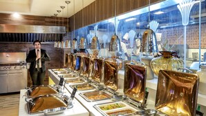 A buffet setup with various food containers and a person standing nearby.