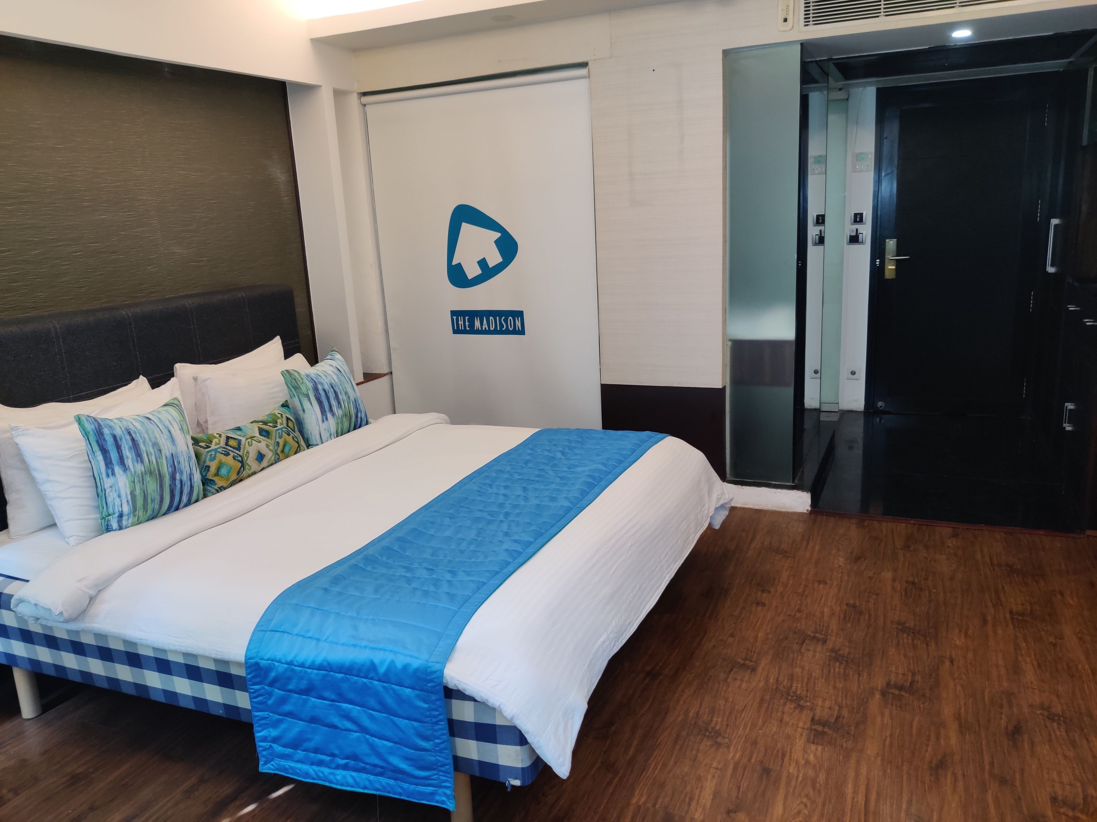 Una habitación de hotel con una cama, una puerta con un letrero y un pasillo.
