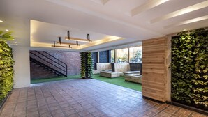 A spacious indoor area with a brick staircase, green artificial grass, and wooden wall panels.