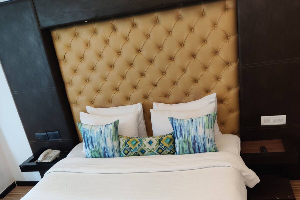 A bed with a tufted headboard, white and blue bedding, and patterned pillows.