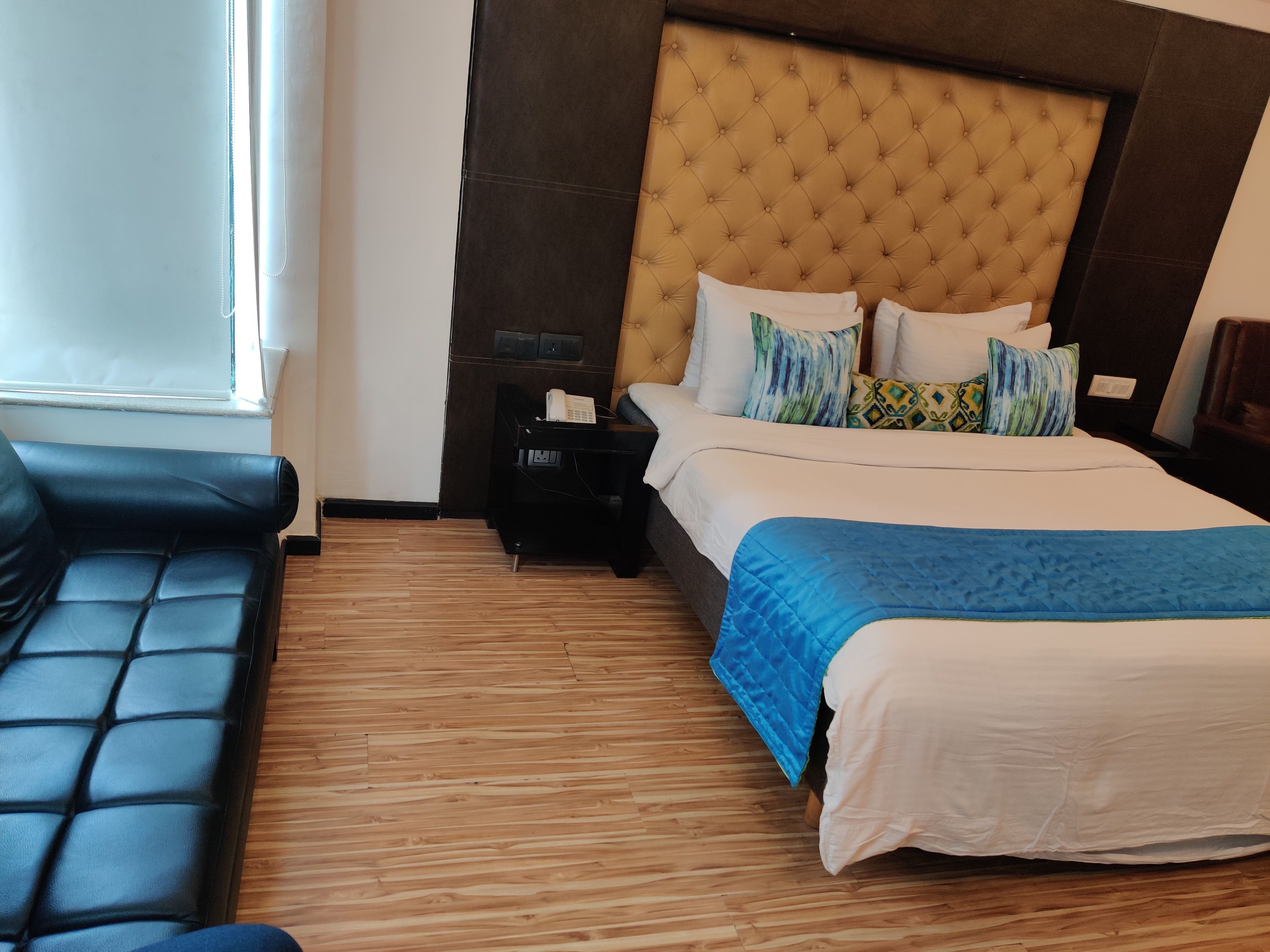 A hotel room with a bed, a nightstand, a telephone, and a window.