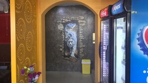 A hallway with a decorative wall, a vending machine, and a trash bin. - Kathmandu Airport Hotel (Kathmandu)