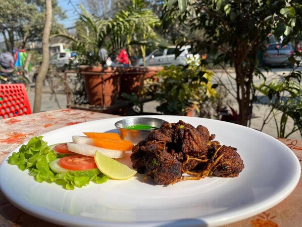 A plate of food with meat, vegetables, and a side of sauce. - Kathmandu Airport Hotel (Kathmandu)