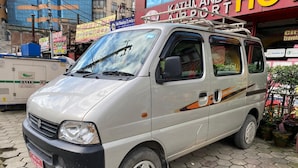 A white van parked on a cobblestone street with a sign for Kathmandu Airport in the background. - Kathmandu Airport Hotel (Kathmandu)