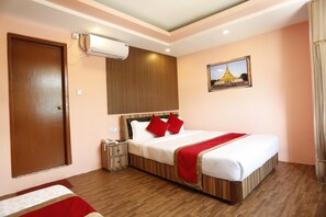 A hotel room with a wooden bed, a nightstand, an air conditioning unit, and a wall-mounted picture. - Kathmandu Airport Hotel (Kathmandu)