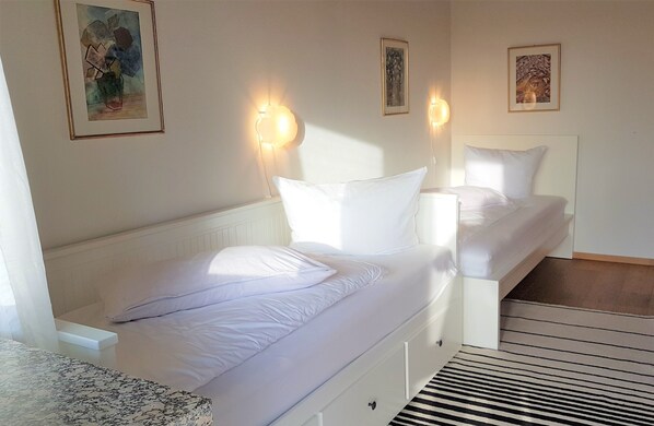 A bedroom with a bed, a bedside table, and a window.