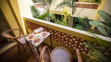 A balcony with wicker chairs, a patterned table, and lush tropical plants.