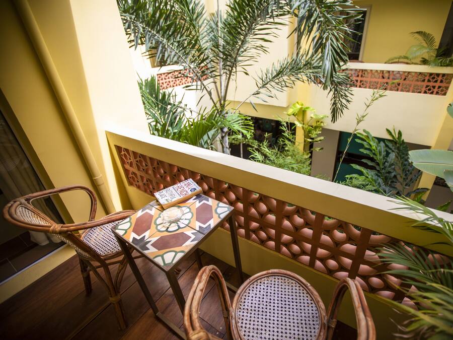 A balcony with wicker chairs, a patterned table, and lush tropical plants.