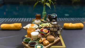 A breakfast tray with various foods and drinks by a poolside.