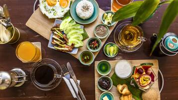 Une table en bois sur laquelle on trouve une variété de plats, notamment du riz, des œufs et de la viande, ainsi que plusieurs petits bols contenant des condiments et un verre de thé.