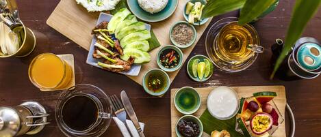 A wooden table with a variety of dishes, including rice, eggs, and meat, along with several small bowls of condiments and a glass of tea.