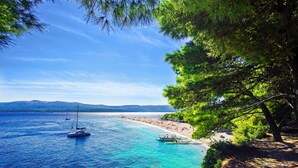 A coastal scene with clear turquoise waters, boats, and a beach. - Zlatni rat Beach Resort (Bol)